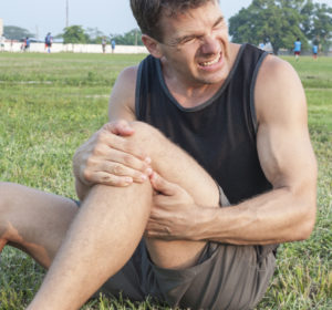 man holding knee in sports injury